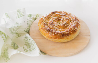Traditional spiral phyllo pie in wooden plate. White background