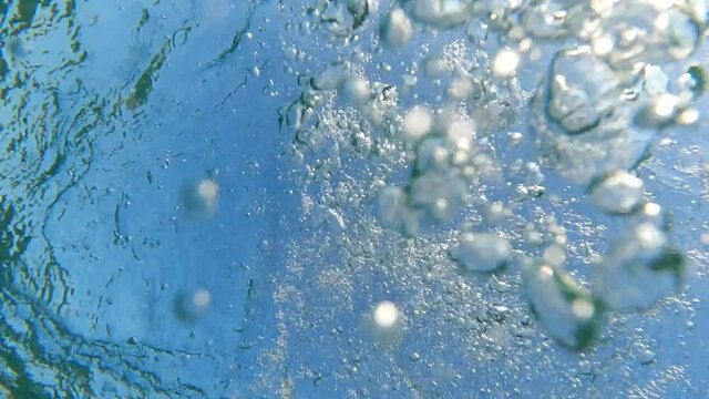Underwater slow motion bubbles moving to surface in turquoise crystal clear pool