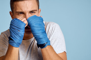 sporty man in blue boxing gloves and t-shirt on blue background practicing punches cropped view