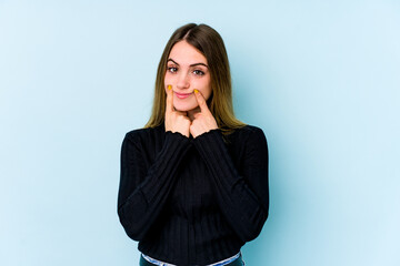 Young caucasian woman isolated on blue background doubting between two options.