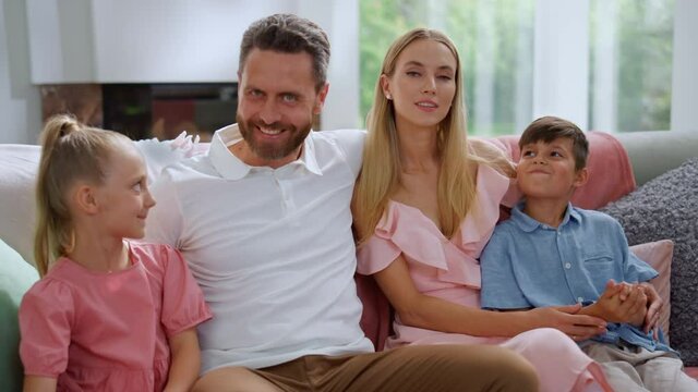 Family sitting on sofa in living room. Woman and man talking with children
