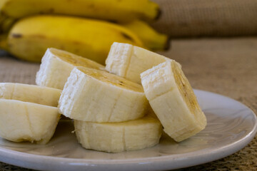 a sliced ​​banana on the plate and a bunch of bananas on the bottom. selective focus