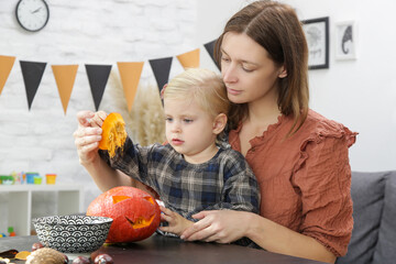 Fototapeta premium Cute little girl preparing Halloween decorations with her mother. Autumn DIY craft at home. 