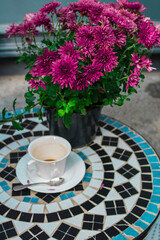 White coffee cup and a pot of pink chrysanthemums