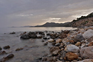 Rocky stretch of coast of the Mediterranean Sea on the Greek Aegean island of Samos with a calm water surface.