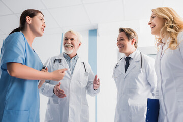 Fototapeta premium Selective focus of doctors looking at nurse with digital tablet while talking in clinic