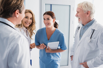 Selective focus of nurse with digital tablet standing near doctors in clinic