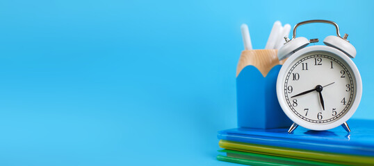 Textbooks and alarm clock on a blue background. Back to school. Concept Education or business. banner