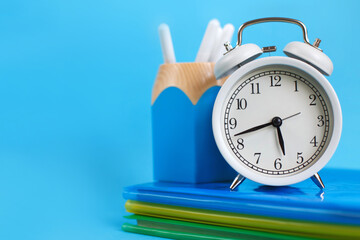 Textbooks and alarm clock on a blue background. Back to school. Concept Education or business