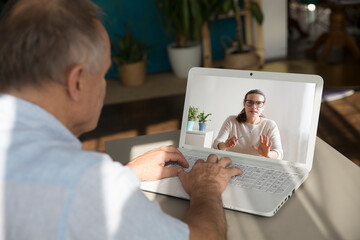 Elderly man watching an online video on laptop at home. Distancing. copy space.
