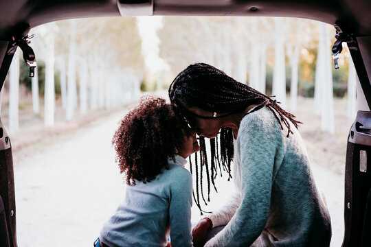 young woman and daughter with foreheads together in a car in forest. Love and family concept
