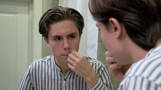 Young guy crushes pimples. Awkward age. Problems with the skin. Dermatology