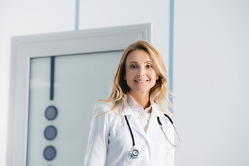 Blonde doctor in white coat looking at camera in hospital