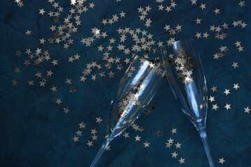 Two clinking champagne glasses with splash of star shaped confetti