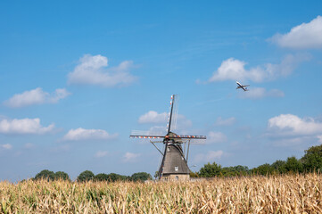 View on grain wind mill in Veldhoven and farmer field with ripe yellow corn ready to harvest