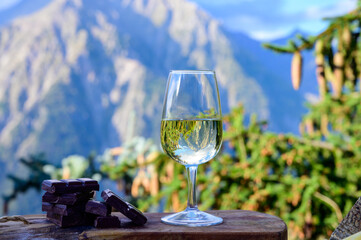 Glass of swiss or savoy dry white wine, pure chocolate with Alpine mountains peaks on background