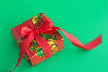Closeup on Christmas gift  with red ribbon on the green background