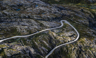Cars driving on a narrow and twisty mountain pass road down below, Norway