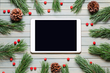 Christmas or new year background on a wooden background. Tablet with a blank screen for greetings. Flat lay, top view, copy space