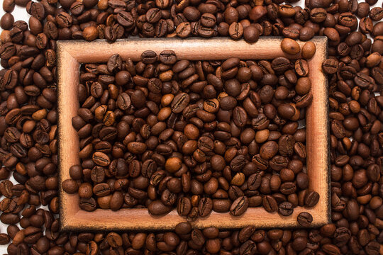 Wooden brown frame on coffee beans background. Concept of coffee drink time.