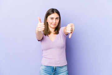 Young caucasian woman showing thumbs up and thumbs down, difficult choose concept