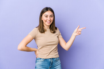 Young caucasian woman smiling cheerfully pointing with forefinger away.