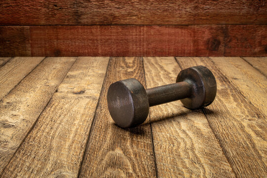 vintage rusty iron dumbbell on grained barn wood background - fitness concept