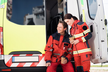 Paramedics in uniform holding coffee to go near ambulance car © LIGHTFIELD STUDIOS