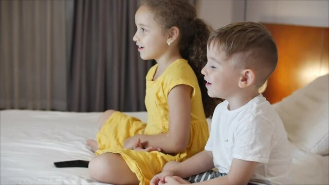 Portrait ute Little Kids While Watching TV on Laptop. Boy and Girl Watch Cartoon on Laptop on Living Room. Concept Video Game, Entertainment, Emotions, Family. Children Brother and Sister Watching TV