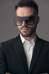 Closeup of confident fashion model wearing sunglasses with hands crossed