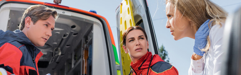 Website header of doctor looking at paramedics near ambulance car outdoors © LIGHTFIELD STUDIOS