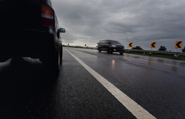 Black compact SUV car stop on wet road during hard rain fall with storm clouds as background,.transportation during bad weather condition concept.