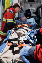 Fototapeta na wymiar Selective focus of paramedics standing near patient on stretcher and ambulance auto