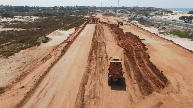 Aerial view of heavy machinery, Articulated truck moving dirt on a new road construction site, heavy equipment top down footage of dump truck

