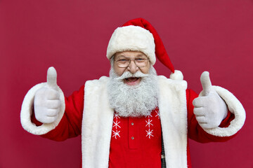 Happy excited funny bearded old Santa Claus wearing costume showing thumbs up hand like gesture...