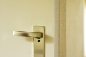 Closeup of silver colored horizontal door handle on white door