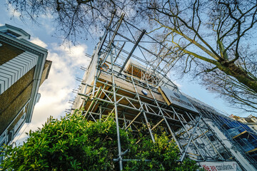 LONDON - MARCH 1, 2020: building in scaffolding next to traditional buildings on a city street,...