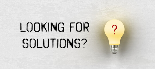 bright lightbulb on paper background with message LOOKING FOR SOLUTIONS?