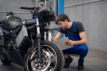 Obraz na płótnie Canvas A machinist inspects a bike. He is wearing a blue uniform