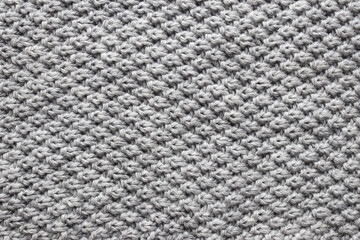 The texture of the woolen knitted gray sweater. Close-up