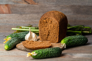 rye bread, fresh cucumbers and garlic on a wooden table