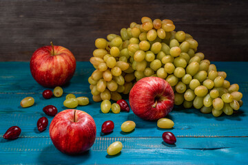 Grapes, apples and a bowl with dogwood on a wooden table
