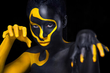 Gesichtskunst. Frau mit schwarzer und gelber Körperbemalung. Junges afrikanisches Mädchen mit bunter Körperfarbe. Ein erstaunliches Modell mit gelbem Make-up. Nahaufnahme Gesicht.