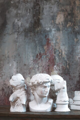 Plaster ancient greek sculptures, statues and heads of hero on wooden table.
