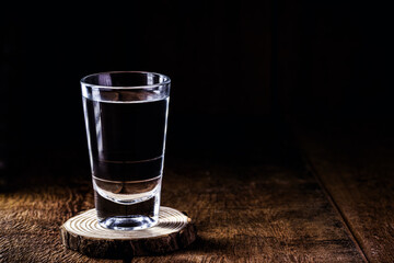 glass of strong distilled alcoholic drink, with space for text, black background. Image for pug or bar