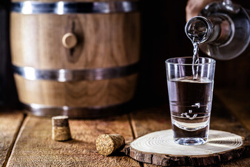 glass of alcoholic drink with bottle, hand filling glass. Image of bar, pug, spirits of the type...