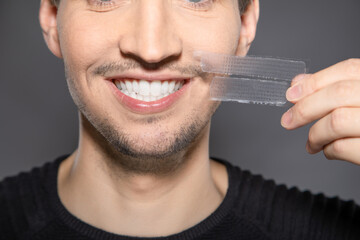 man with whitening stripes  next to  his face smiling happy with fresh dental teeth