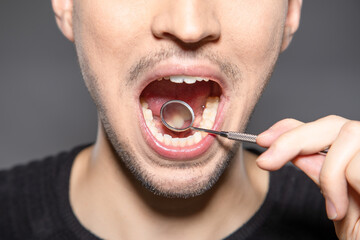 person with mirror in mouth is checking the backside of front teeth to see if there is caries or...