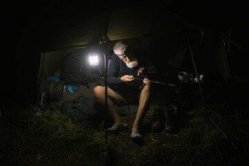 Mature man camping at night and prepare fishing rod