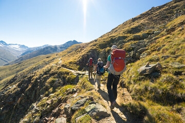 Three hikers on a mountain trail in the alps